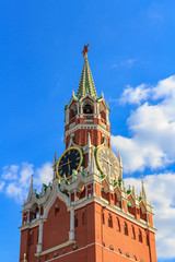Fototapeta na wymiar Spasskaya tower of Moscow Kremlin with ruby red star and chimes clock on a background of blue sky with white clouds at sunny day