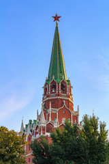 Fototapeta na wymiar Tower of Moscow Kremlin with red ruby star against blue sky and green trees at sunny morning
