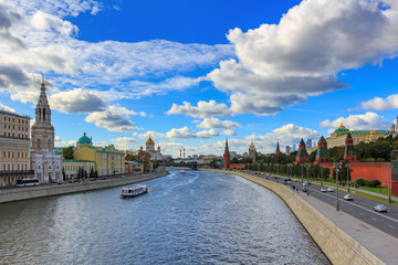 Fototapeta na wymiar View of Moskva river and Kremlevskaya embankment in sunny day against blue sky with white clouds