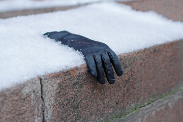 Forgotten leather glove lies on a snow-covered granite fence