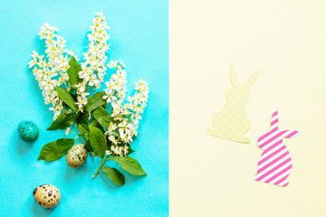 Spring flowers, Easter eggs, bunny on a blue and yellow background. Minimal easter concept. Flat lay, top view background.