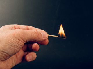 Match with a fire flame burning being held by a hand