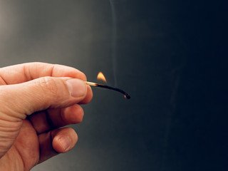 Match with a fire flame burning being held by a hand