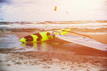surfboard on the beach, kitesurfing in the background