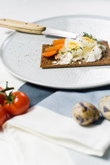 Quail egg toast. Ingredients tomatoes, egg, cheese, rye bread. White background, side view