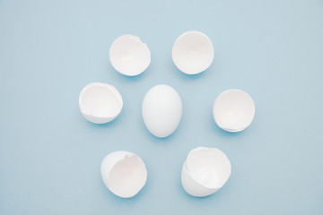  Broken white egg shells around the whole egg, isolated on blue background