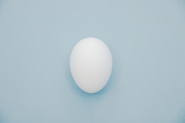 One raw chicken egg on blue background top view isolated