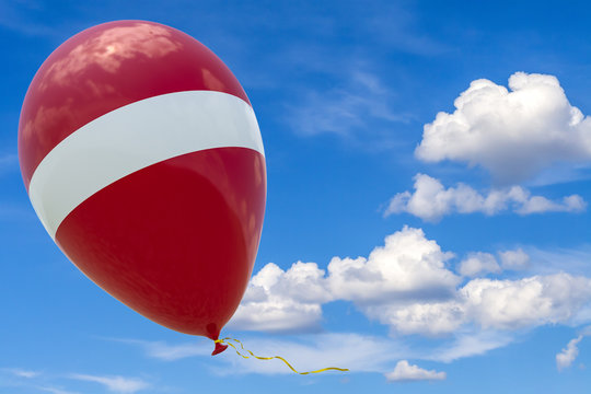 Balloon with the image of the state flag of Latvia, flying against the blue sky.