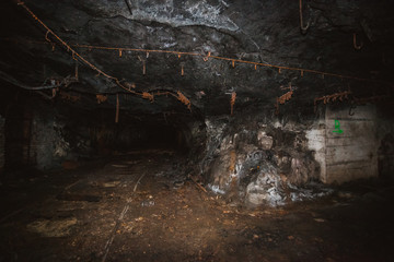 Inside old closed coal mine; dangerous tunnels full of dirt, lots of abandoned rusty equipment, devastated industrial place