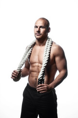 Young adult strong man holding rope around his neck. Posing in front of black background.