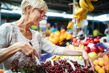 Picture of mature woman at marketplace buying vegetables