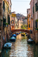 Fototapeta na wymiar VENICE / ITALY - OCTOBER 11, 2010: Citycsape of water duct and gondola, colorful narrow venetian street and canale, best place for romantic trip
