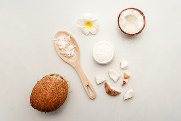 Fototapeta na wymiar Coconut with jars of coconut oil and cosmetic cream on wooden background