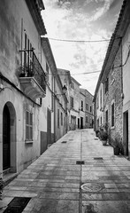 Black and white picture of a narrow steep street in Alcudia old town, Mallorca, Spain.