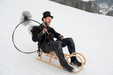 Schornsteinfeger auf Holzschlitten, Rutschpartie im Schnee