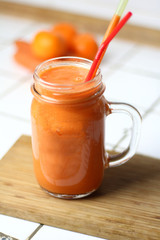 Orange healthy refreshing veggie carrot smoothie in a transparent glass with tubules on a white table by the day healthy nutrition diet detox