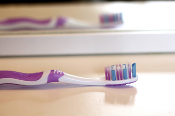 Pink toothbrush on the white shelf in the bathroom is reflected in the mirror , mornin care, tooth care and health