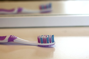 Pink toothbrush on the white shelf in the bathroom is reflected in the mirror , mornin care, tooth care and health