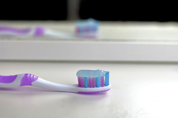 Pink toothbrush on the white shelf in the bathroom is reflected in the mirror , mornin care, tooth care and health