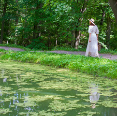 woman in white dress walking in the park on a summer day