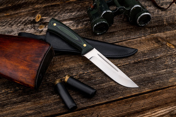 All-metal knife with a handle of colored carbon on a natural wooden plank background