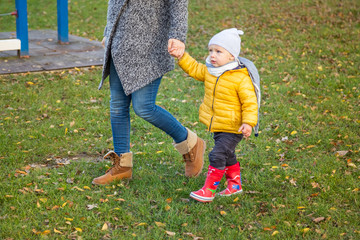 Fototapeta premium Mother and infant boy walking on grass in a park, Zagreb, Croatia.