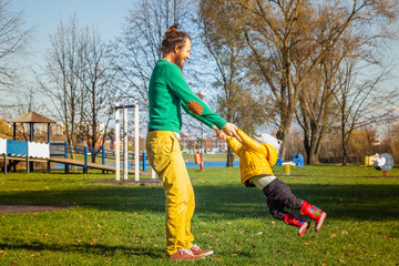 Fototapeta premium Father rotate infant son in public playground, Zagreb, Croatia.