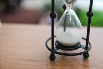 Sand running through the bulbs of an hourglass measuring the passing time in a countdown to a...