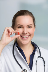 Eine lächelnde Apothekerin hält eine Tablettenkapsel in der Hand