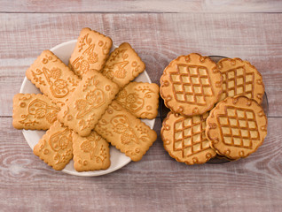 Cookies of two kinds in saucers on wooden background