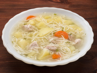 Soup in a white plate on a brown wooden background