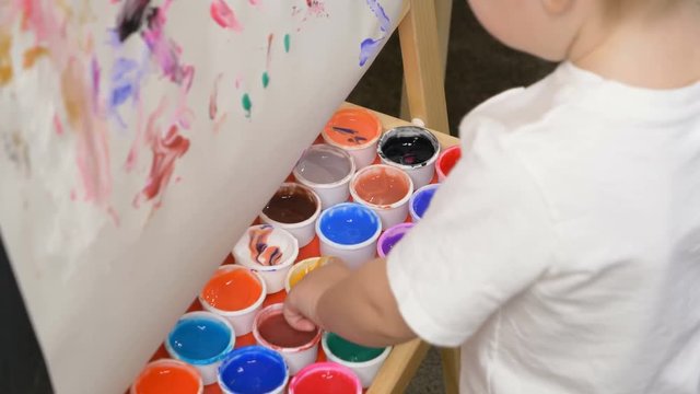 Cute little boy (toddler, two years old) is painting. Washable finger paints for Babies Kids. Art, creative, early childhood education to children concept, kindergarten, pre-primary, nursery school.