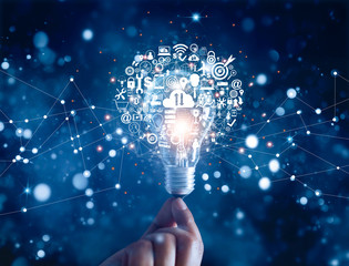 .Hand holding light bulb and business digital marketing innovation technology icons on network...