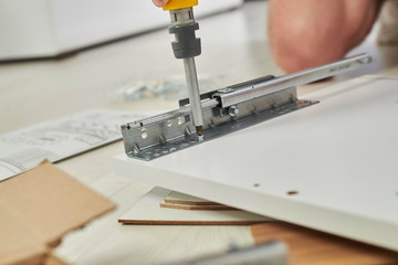 The furniture assembler joins together the two parts of the ready-to-assemble furniture with cam lock connections and wooden dowel pin, flat pack furniture assembly service, snap-together joints