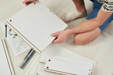 The furniture assembler joins together the two parts of the ready-to-assemble furniture with cam...