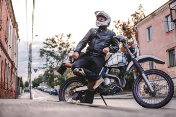 Fototapeta na wymiar Handsome rider guy in helmet with off road enduro motorcycle at day time. Brutal urban lifestyle