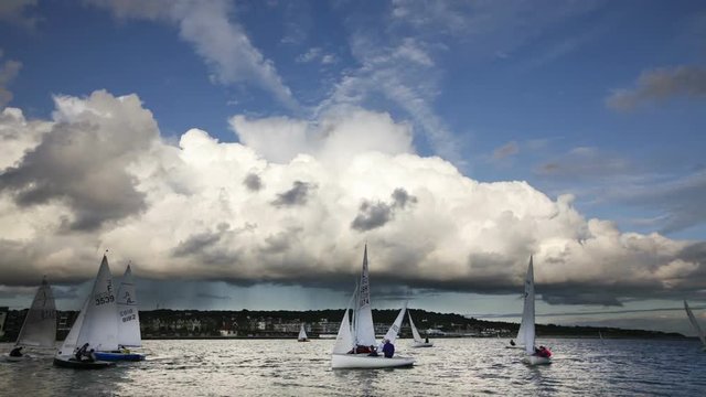 Dramatic rain clouds pass over dinghies sailing on lake