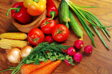 Appetizing vegetables. Tomatoes, radishes, cucumbers, carrots, peppers, eggplants, parsley on a wooden table