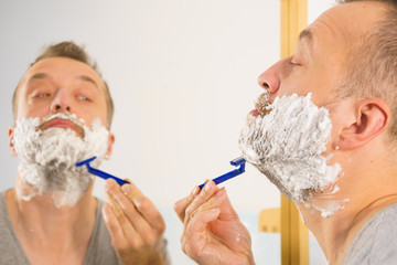 Guy shaving his beard in bathroom