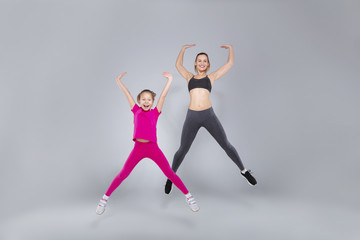 Fototapeta na wymiar Beautiful woman and her daughter are jumping at the gym