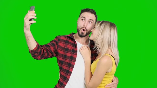 Young man taking selfie with woman on green screen. White male and female, chroma key.