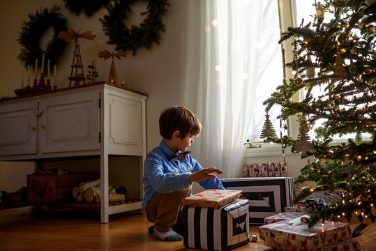 Boy kneeling in front of a Christmas tree looking at gifts
