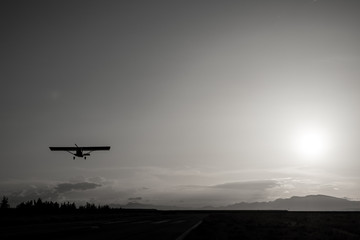 Light aircraft taking off against sunset, backlit