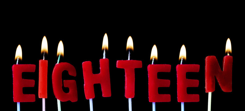 Eighteen spellt out in red birthday candles against a black background