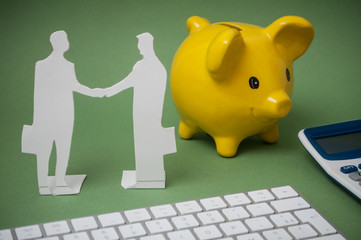 concept business man with paper silhouettes on desk with yellow piggy bank on background