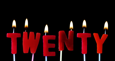 Twenty spellt out in red birthday candles against a black background