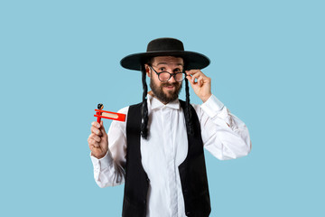 Portrait of a young orthodox Hasdim Jewish man with wooden Grager Ratchet at Jewish festival of Purim at studio. The purim, jewish, festival, holiday, celebration, judaism, pastry, tradition, cookie