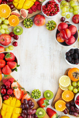 Healthy raw breakfast background, cut fruits, strawberries raspberries oranges plums apples kiwis grapes blueberries mango persimmon, on white table, copy space, top view, selective focus