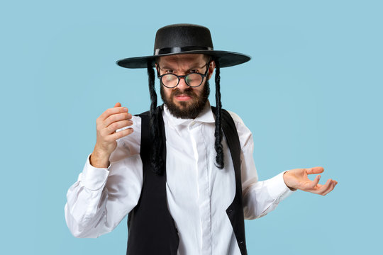 Portrait of a young orthodox Hasdim Jewish man at Jewish festival of Purim at studio. The purim, jewish, festival, holiday, celebration, judaism, pastry, tradition, cookie, religion concept.