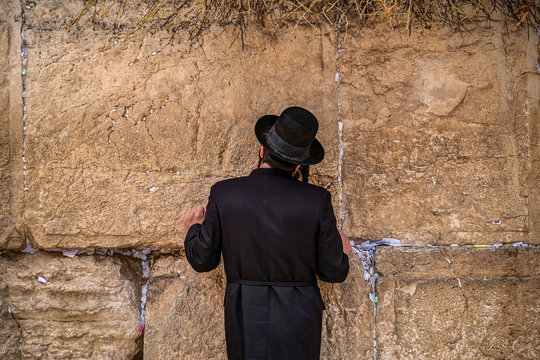 Believing Jew pray near the wall of crying in a big black hat